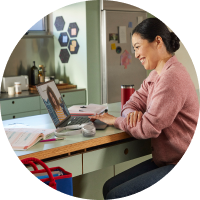 Person takes a video meeting from the kitchen while working at home via Webex Meetings on a laptop.